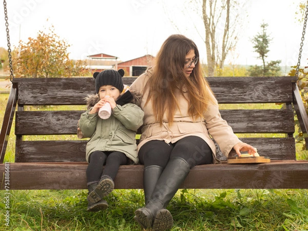 Fototapeta mother and child have a snack on a bench