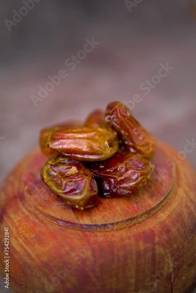 Fototapeta Front view of dried dates or kurma on wooden plate isolated 