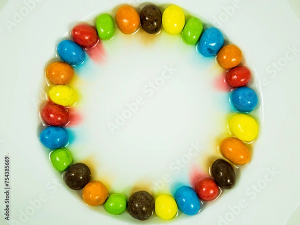 Obraz Colored oder bunte Schokokugeln liegen im Wasserbad und verlieren Farbe.	