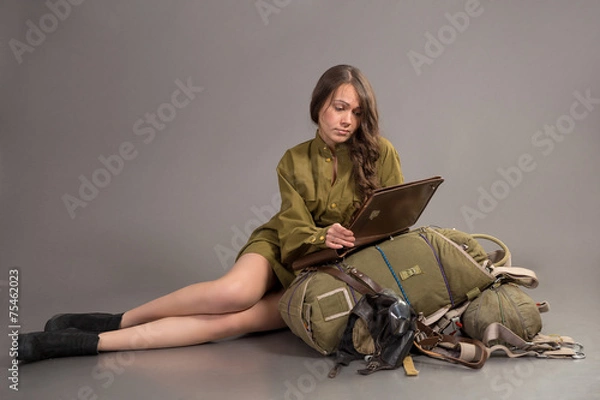 Fototapeta girl in Soviet army uniform sits on parachute with bag board