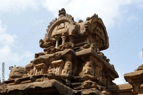 Fototapeta Kailasanathar Temple tower against blue sky background. Ancient Hindu temple gopuram with carved sandstone sculptures of God.