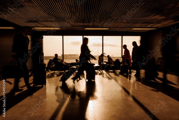 Fototapeta Pilot and Stewardess at airport with people sitting and walking with luggage through the departure area, motion blur shot. Travelers and transport concepts.