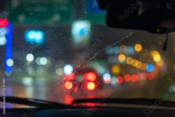 Fototapeta Inside the car during rainfall with a blurred abstract background outside stop lights