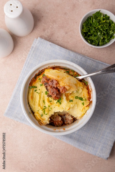 Fototapeta Shepherd's pie in a portioned white baking dish. Homemade traditional casserole (gratin) with minced meat and mashed potatoes. Selective focus, close-up.