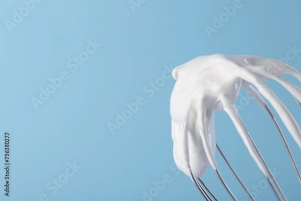 Fototapeta Whisk with whipped cream on light blue background, closeup. Space for text