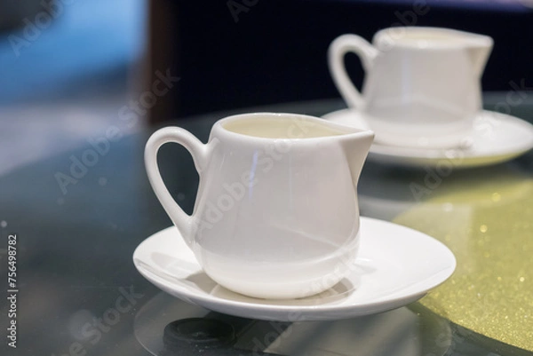 Fototapeta Cup of pouring cream on the table in the cafe