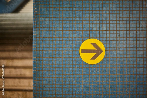 Fototapeta blue tiled wall with small tiles and yellow arrow in subway