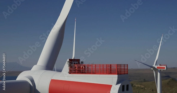 Obraz Large wind turbine rotating blades . Engineer performing repairing and maintenance works on top of wind turbine nacelle house.