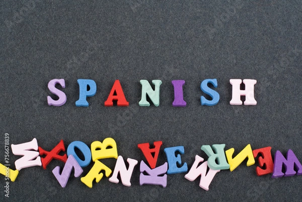 Fototapeta SPANISH word on black board background composed from colorful abc alphabet block wooden letters, copy space for ad text. Learning english concept.