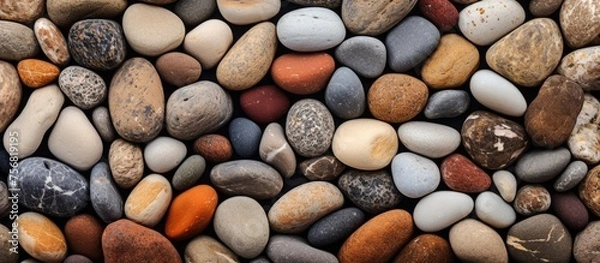 Fototapeta Closeup of a pile of rocks of varying colors and sizes made up of pebbles, cobblestones, and gravel. The natural building material forms a beautiful rectangle pattern