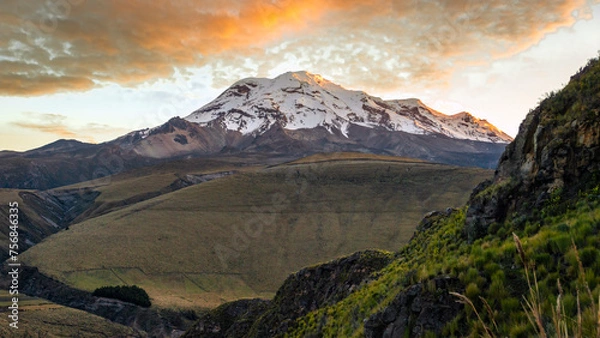 Obraz High Andes view of the north face of the Chimborazo volcano at dawn with its summit and the clouds above illuminated by the orange light of the sunrise
