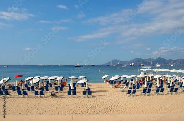 Fototapeta A beach on La Croisette in Cannes in the south of France, with deckchairs, umbrellas and jetty.