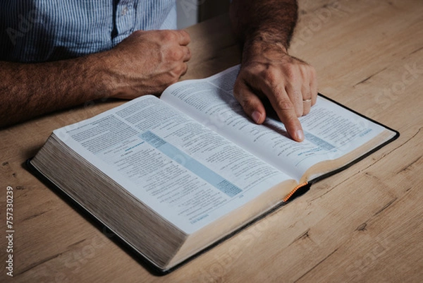 Fototapeta Man is reading the bible pointing with his finger at the text