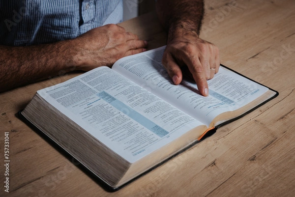 Fototapeta Man is reading the bible pointing with his finger at the text