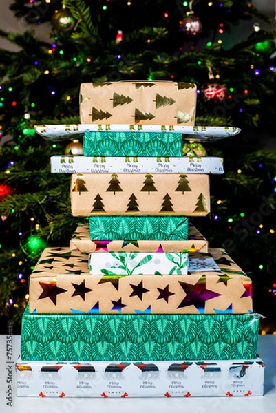 Fototapeta Christmas presents stacked randomly in front of the tree