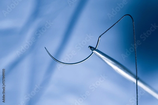 Fototapeta Closeup photo of a needle holder and half circle needle with suture during operation.