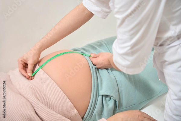 Fototapeta Close-up nurse of gynecologist measuring size of pregnant woman belly
