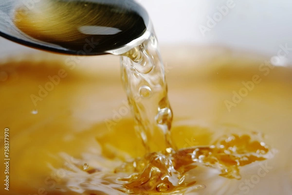 Obraz Macro shot of golden liquid splash made up of melting gummy bear in hot water