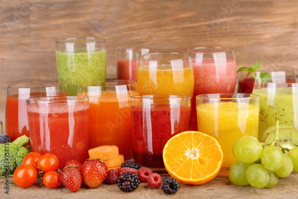 Fototapeta Glasses of tasty fresh juice, on wooden table.
