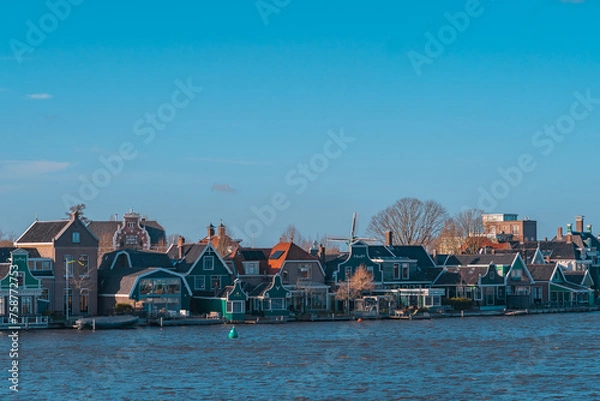Obraz Beautiful Dutch scenery panorama of Zaanse Schans village in Netherlands in spring time. Ancient houses brightly colored at the water's edge against a blue sky in sunny weather