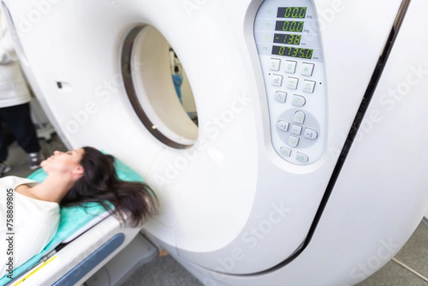 Fototapeta Pretty, young woman goiing through a Computerized Axial Tomography CAT Scan medical test examination in a modern hospital