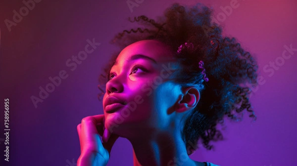Obraz A young woman, illuminated by the dreamy hues of pink and purple neon lights, looks upward with a hopeful expression, symbolizing optimism and the vibrancy of youth.