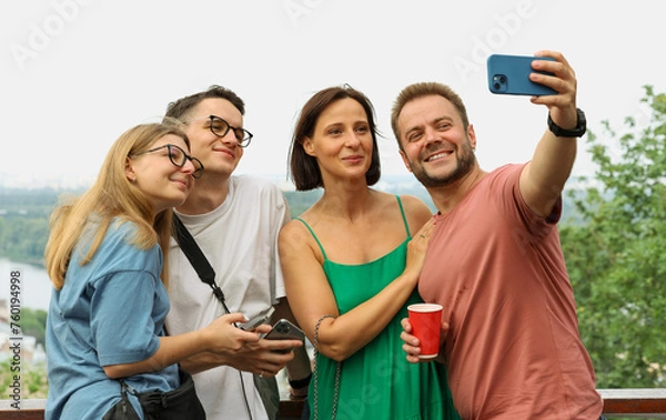 Fototapeta a group of friends relaxing in the city taking a selfie watching a video