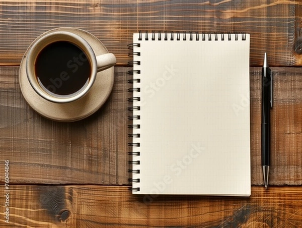 Obraz An empty notebook with a pen on a wooden surface next to a cup of black coffee.