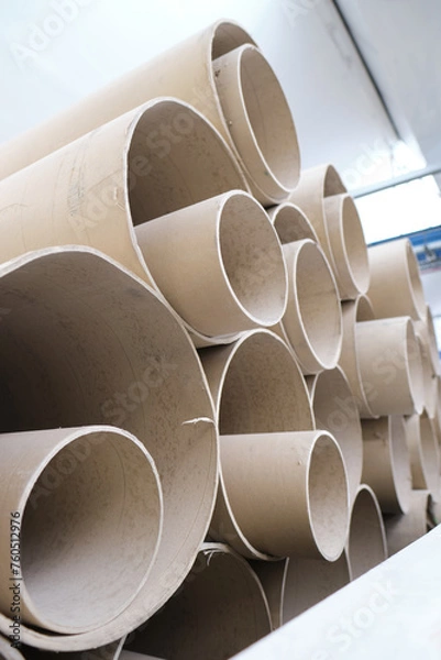 Fototapeta An industrial stack of empty paper cardboard tube rolls waiting to be recycled in a warehouse setting. Industrial waste management. Recycle helping the environment.