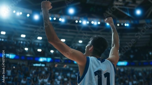 Fototapeta A basketball player celebrates victory, unleashing shouts of joy against the backdrop of a basketball stadium. Emotional celebration of winning the game