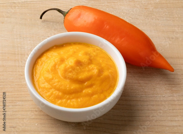 Fototapeta Fresh raw Peruvian Aji Amararillo pepper and a bowl with  Aji Amarillo sauce close up  