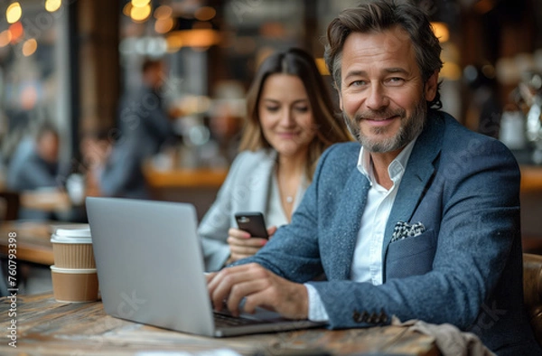 Obraz A man and woman in formal wear smiling while using a laptop at a leisure event