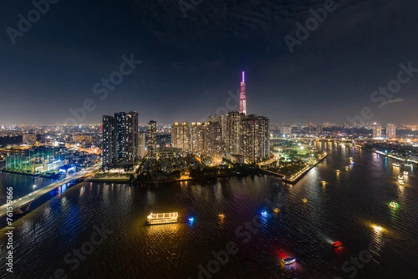 Fototapeta At night on the tallest building in Vietnam, there are boats running on the Saigon River. Photo taken in June 2023