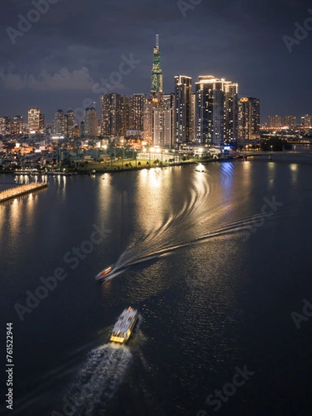 Fototapeta At night on the tallest building in Vietnam, there are boats running on the Saigon River. Photo taken in June 2023
