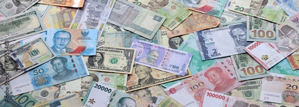 Obraz Many banknotes of different currency. Background of big amount of random money bills close up