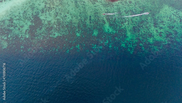 Fototapeta Boats crossing shallow waters of coral reef at the edge of deep blue sea. Aerial view, Phi Phi island, Krabi, Thailand.  