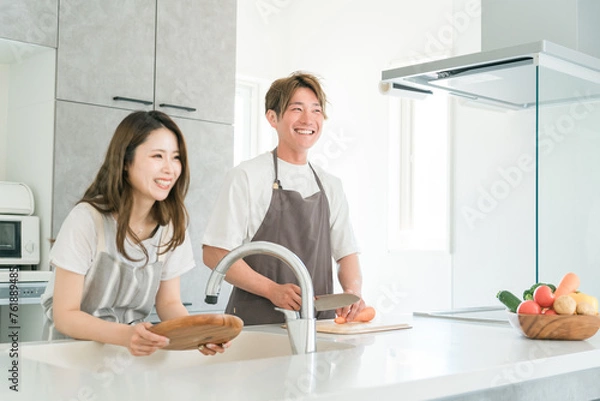 Fototapeta 家のキッチンで一緒に料理を作る若いアジア人夫婦（お皿洗い・包丁）
