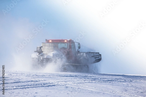 Obraz Ratrak in a spray of snow against the blue sky. Toned