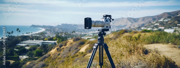 Fototapeta A camera on a tripod is set up on a hill overlooking the ocean.