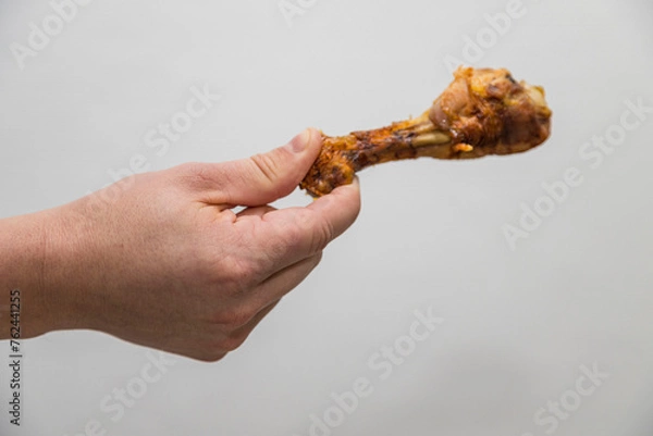 Fototapeta Caucasian man holds a crispy cooked a chicken leg