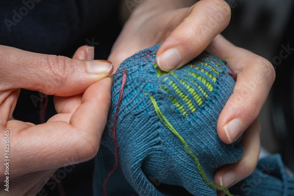 Fototapeta Mending clothes. Visible mending repairing sock. Darning old socks, reducing waste, slow fashion. Repair concept, selective focus.