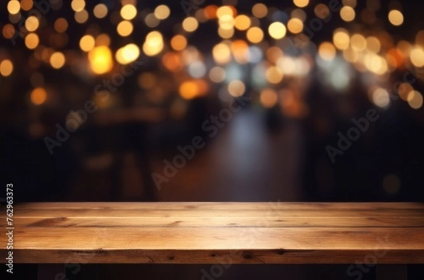 Fototapeta Empty wooden table top with blurred background of bar or cafe at night for product display montage, banner design.