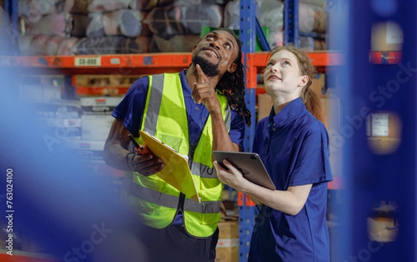 Fototapeta Multiracial manager train female technician working job in warehouse and logistic professional occupation. Storehouse supervisor diverse group of people discussing inventory storage, order delivering