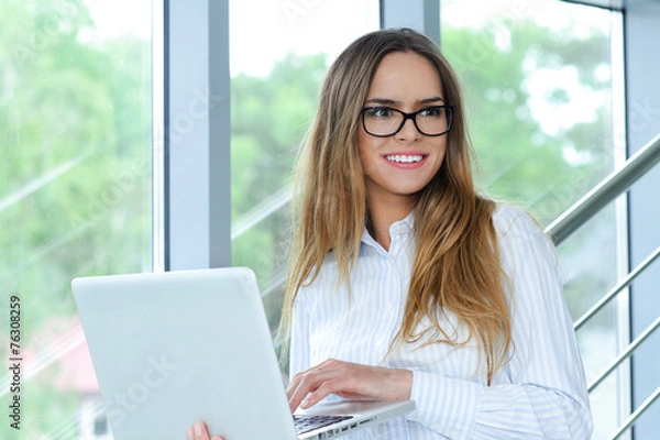 Fototapeta Portrait of a smiling successful businesswoman with computer