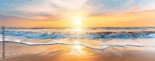 Fototapeta A beautiful sunrise over the ocean, with golden sunlight reflecting on the sand and waves crashing onto it