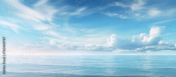 Fototapeta Calm ocean under blue sky with distant clouds