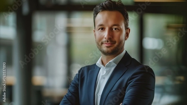 Fototapeta a businessman with his arms crossed standing in front of a building with a glass door and a window behind him