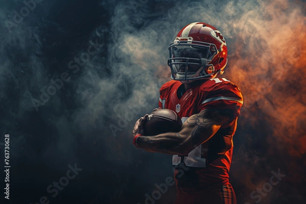 Fototapeta A football player is holding a football in his hands.