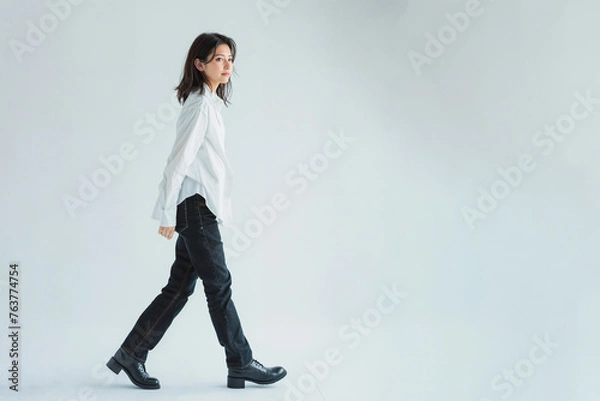 Obraz 白いシャツとデニムパンツ姿の日本人女性が歩いている