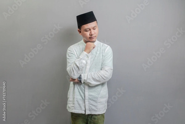 Fototapeta Asian muslim man thinking worried about a question, concerned and nervous with hand on chin